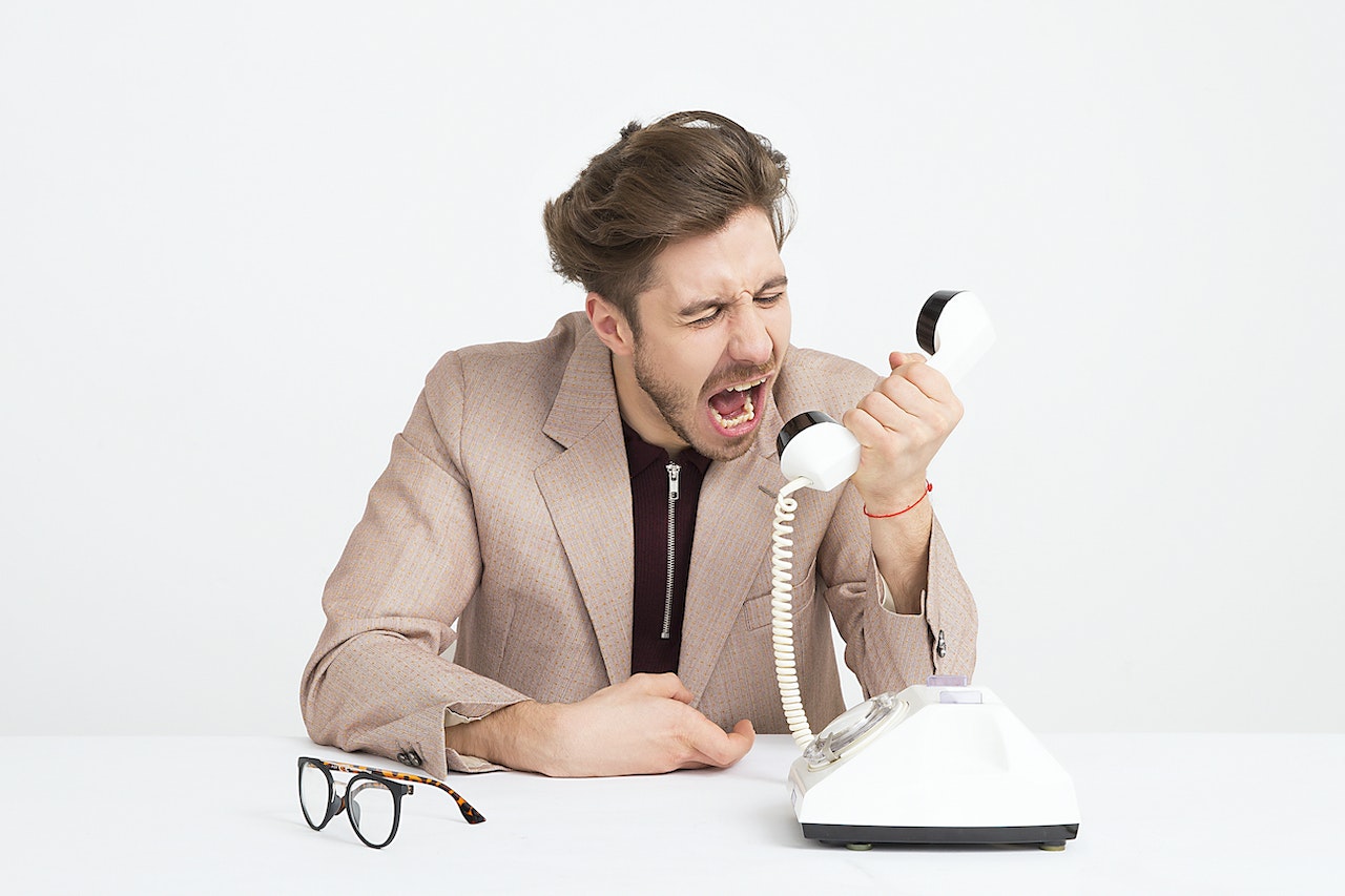 angry person shouting into a telephone